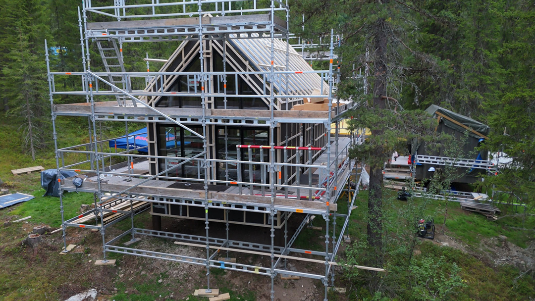 Hytta omringet av stillas under oppføring.